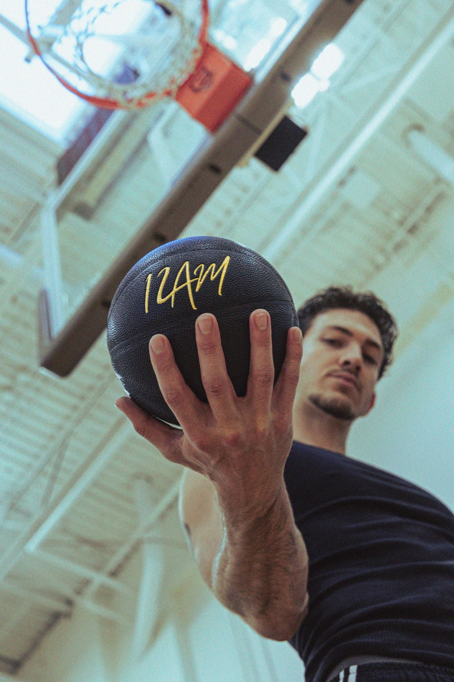 Basketball player holding a matte-black 12AM weighted basketball beneath the hoop