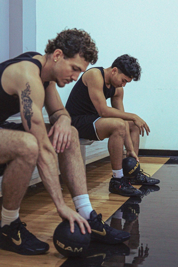 Two basketball players resting on the bench between training reps